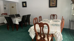 En matplats med ett bord dukat för sex personer, omgivet av trästolar. Där finns också ett litet bord med en vit duk och en tekanna på. Väggarna är dekorerade med inramade bilder och en dörr med en skylt.
