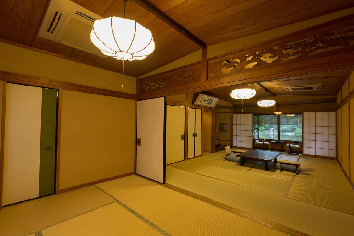 Um quarto japonês tradicional com tatames, portas deslizantes e uma mesa baixa com bancos.