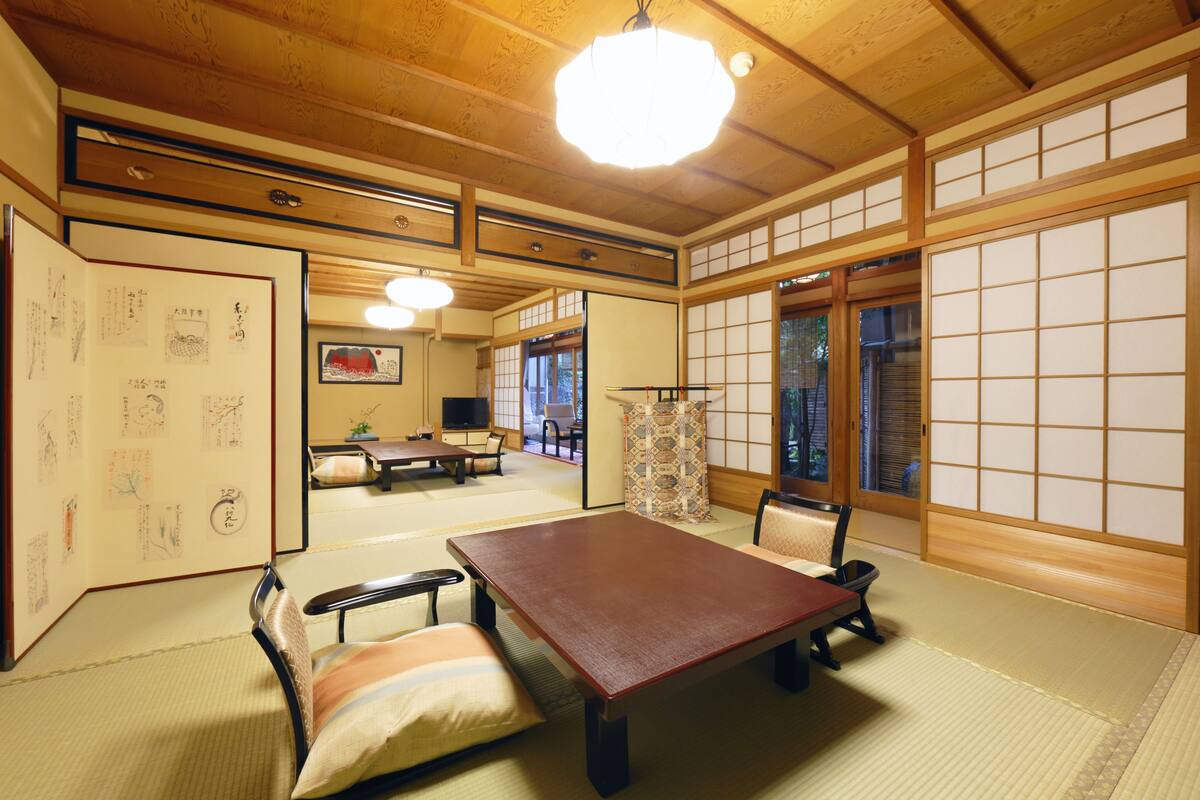 Um quarto japonês tradicional com tatames, uma mesa baixa e biombos shoji.