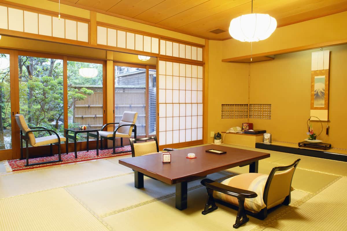 Um quarto japonês tradicional com piso de tatame, uma mesa baixa e cadeiras.