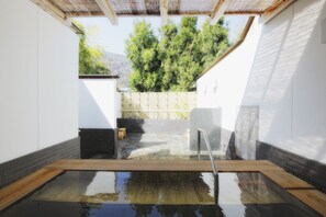 A hot spring bath with a wooden deck, stone steps, and a view of trees and mountains. - Arashiyama Benkei (Kyoto)