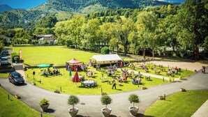 A spacious outdoor area with tables and chairs, surrounded by lush greenery and a mountain backdrop. - Carré Py' Hôtel (Bagnères-de-Bigorre)