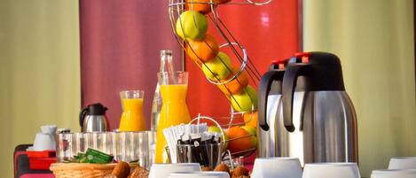 Une table dressée pour le petit-déjeuner, avec une présentation de fruits, des pots de café et divers aliments pour le petit-déjeuner.