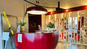 A reception area with a red spherical desk, a large pendant light, a ski leaning against the wall, and a potted plant. - Carré Py' Hôtel (Bagnères-de-Bigorre)