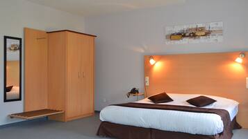 Une chambre d’hôtel comprenant un lit, une armoire, une table de chevet avec une lampe et une œuvre d’art accrochée au mur.