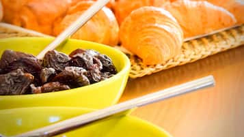 Una mesa de buffet con diversos alimentos, como cruasanes, frutas y un bol de frutos secos.