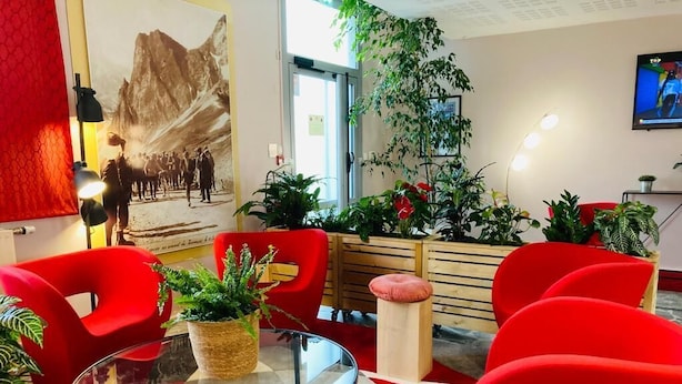A modern interior with red chairs, a glass table, and various potted plants. - Carré Py' Hôtel (Bagnères-de-Bigorre)