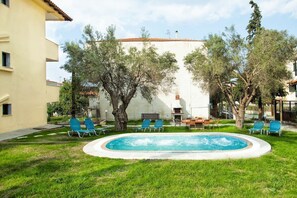 A swimming pool surrounded by green grass and trees, with blue lounge chairs and a table. - Lemon Garden Villa (Kassandra)