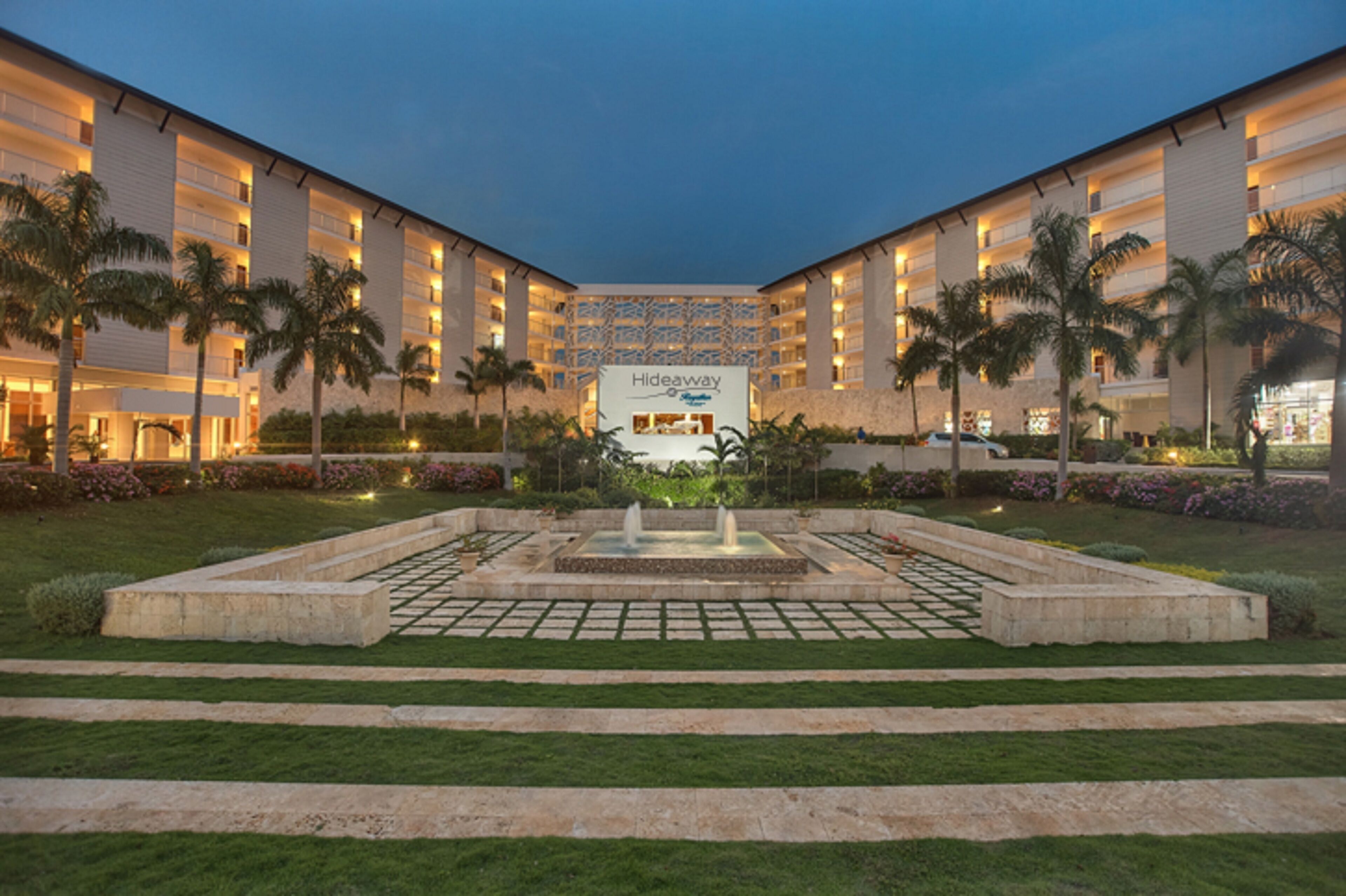 Un hotel con un patio central, palmeras y una fuente.