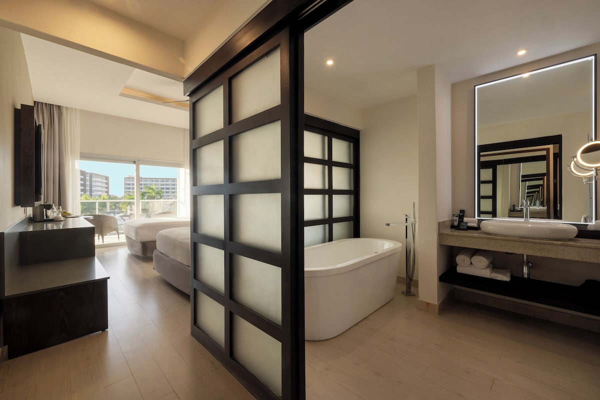 A modern bathroom with a bathtub, a large mirror, and a vanity.