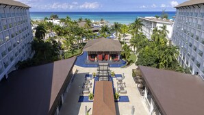 A resort with a central pool, multiple lounge areas, and a view of the ocean.