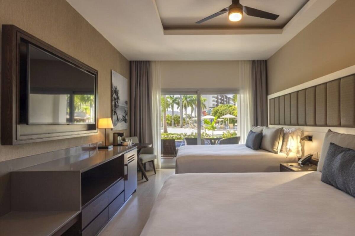 A hotel room with a bed, a desk, a TV, and a view of the outdoors.