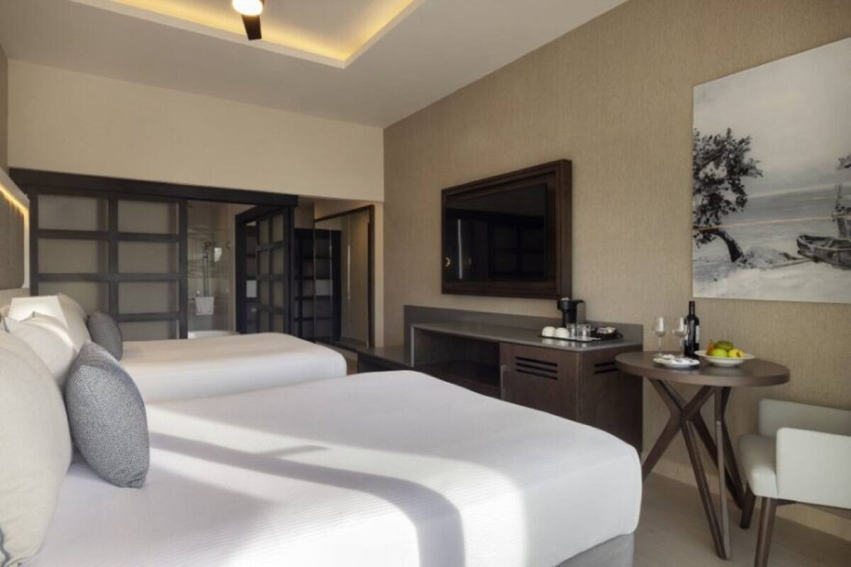 A hotel room with a large bed, a desk, a chair, and a dining table.