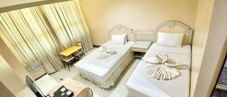 A hotel room with two beds, a desk, and a chair.
