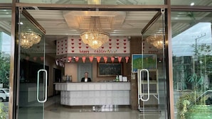 Un hall d'hôtel avec une entrée en verre, un comptoir d'accueil et un lustre.