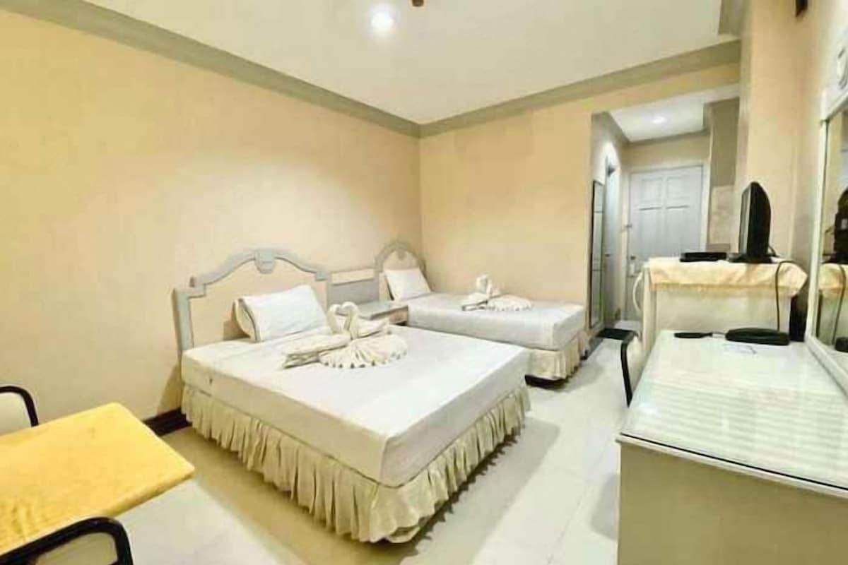 A hotel room with two beds, a bedside table, a chair, and a mirror.