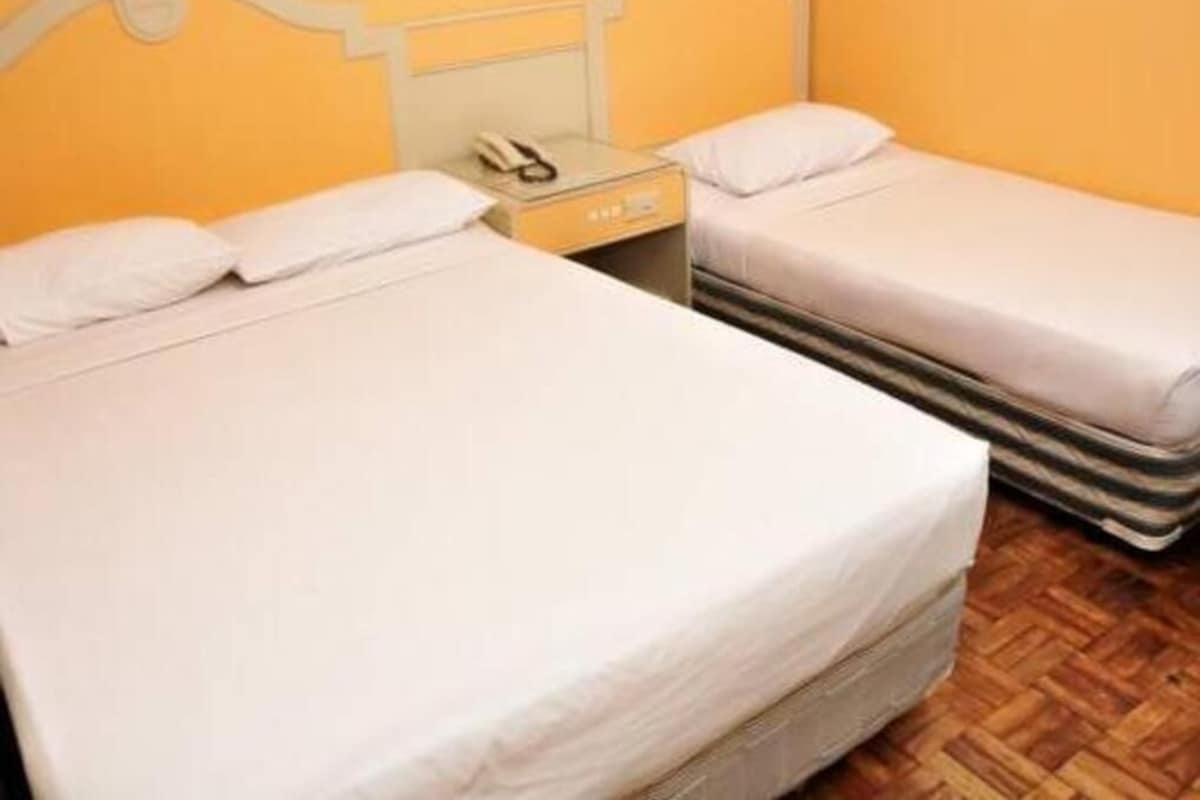 A room with two beds, a bedside table with a phone, and a small cabinet.