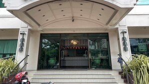 L’entrée de l’hôtel Cebu Northwinds, avec sa façade en verre, son auvent vert et un escalier menant à l’entrée.