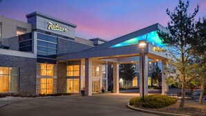 Un hotel Radisson con fachada moderna, ventanas amplias y una zona de acceso cubierta.