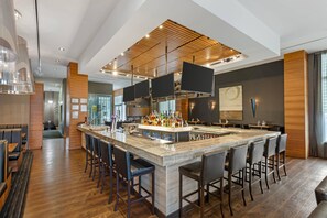 A modern bar area with a central island, bar stools, and overhead lighting. - Radisson Hotel & Conference Centre Calgary Airport (Calgary)