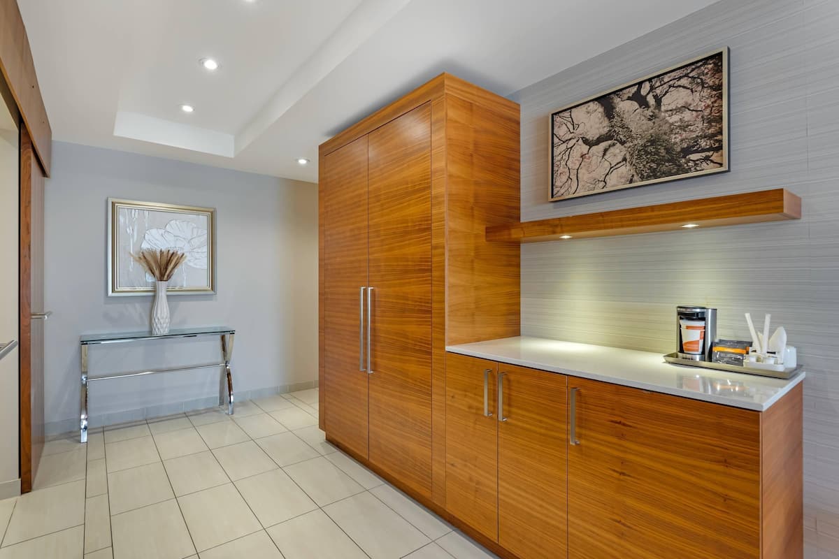A modern kitchen with wooden cabinets, a glass console table, and a painting on the wall.