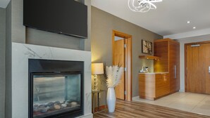 Un salón moderno con chimenea, armarios de madera y un televisor montado en la pared.