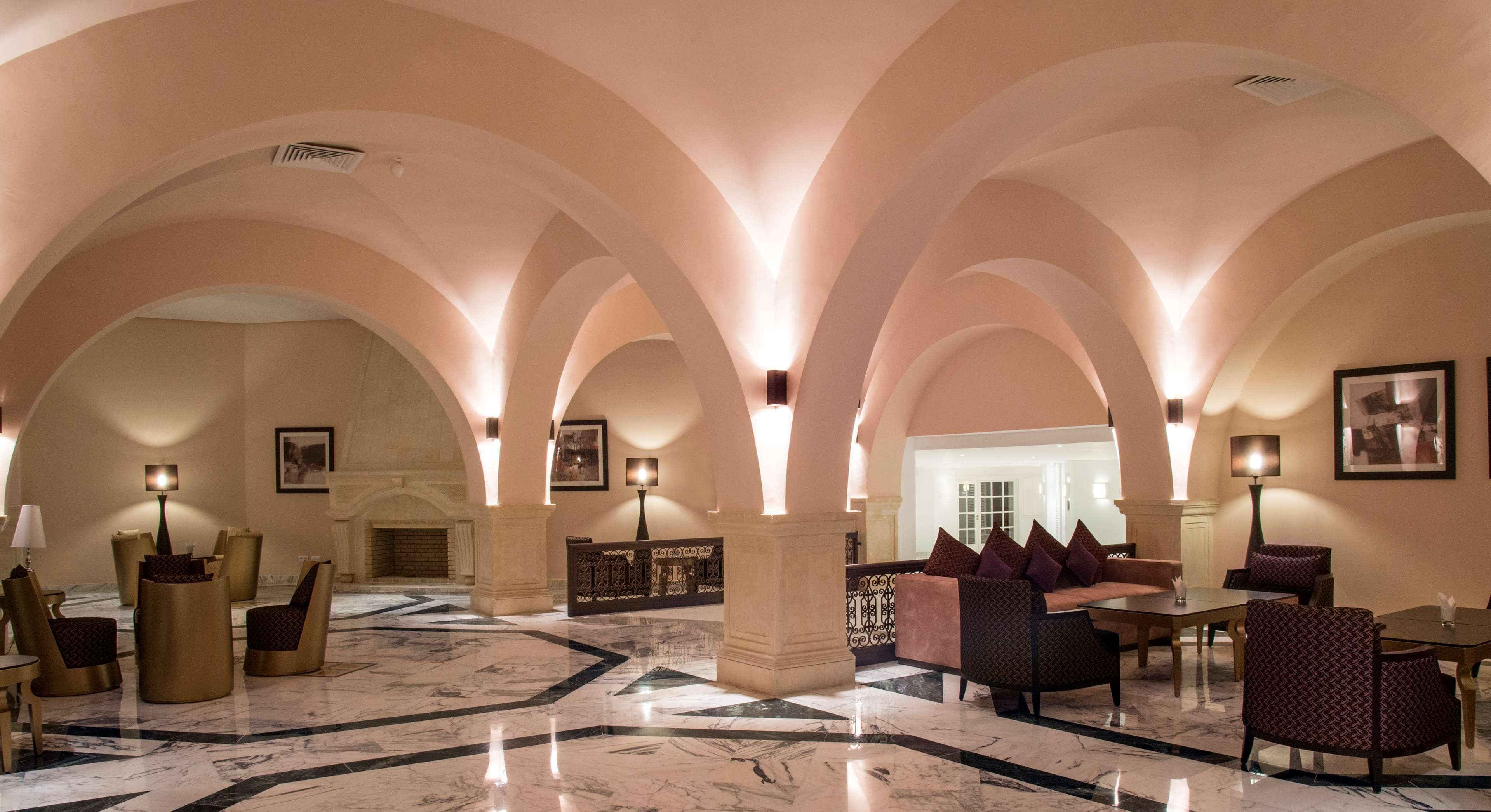 Un'ampia hall con pavimento in marmo, una reception, zone relax e un camino.