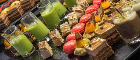 A variety of desserts including macarons, cakes, and beverages on a tray.