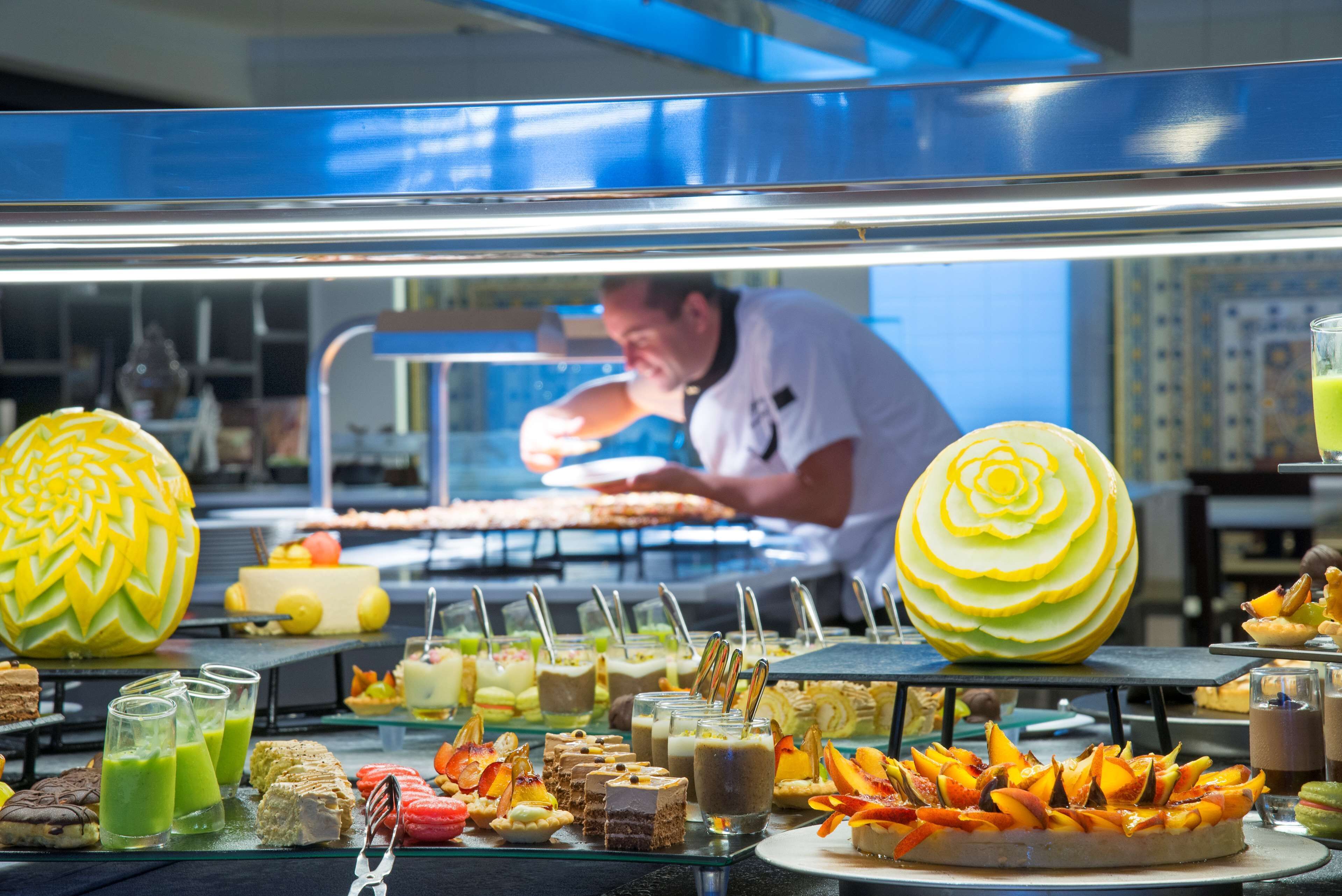 Un buffet proposant une variété de plats, et un chef cuisinant en arrière-plan.