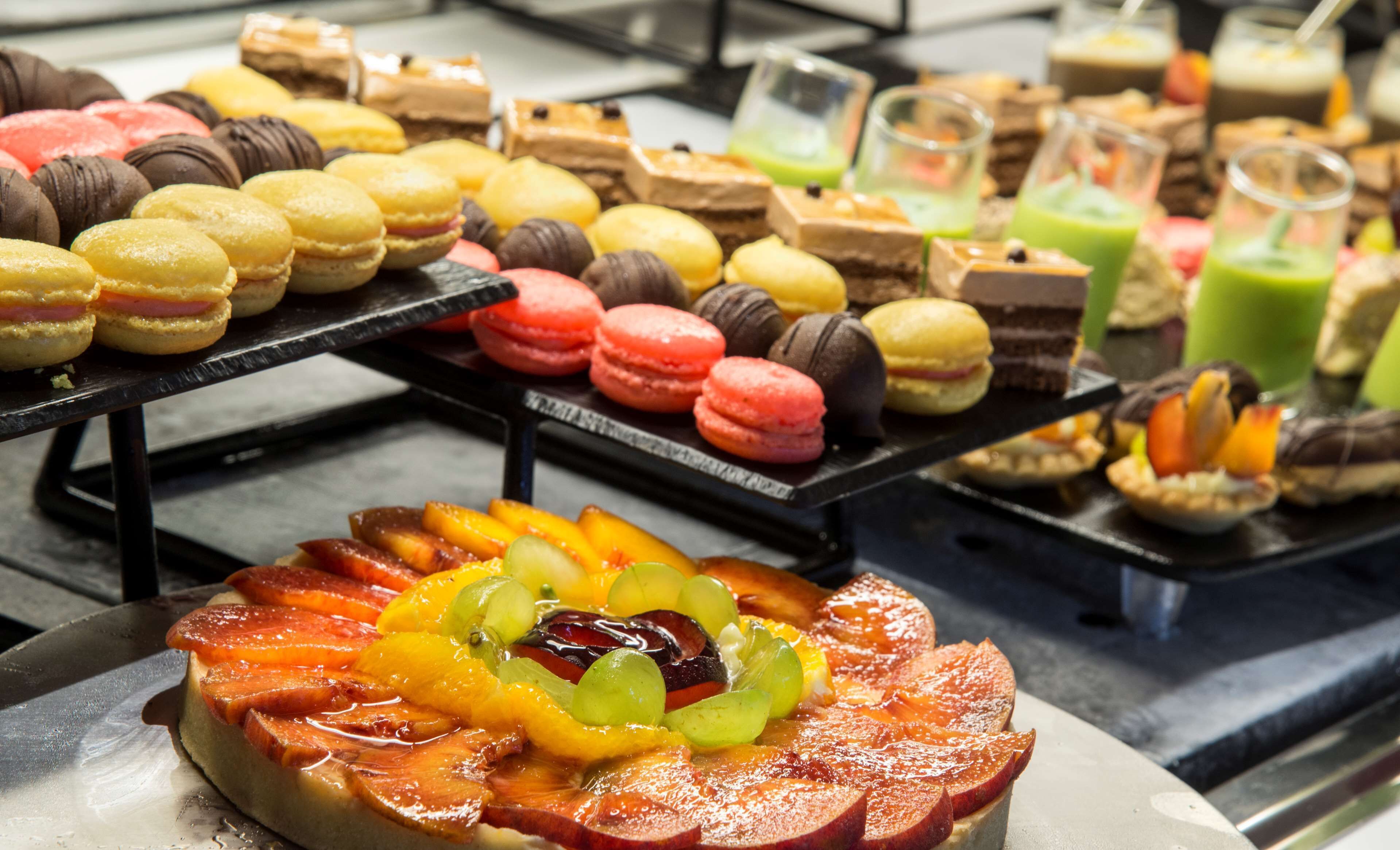 Variedad de postres a la vista, incluyendo macarons, tartas y arreglos de frutas.