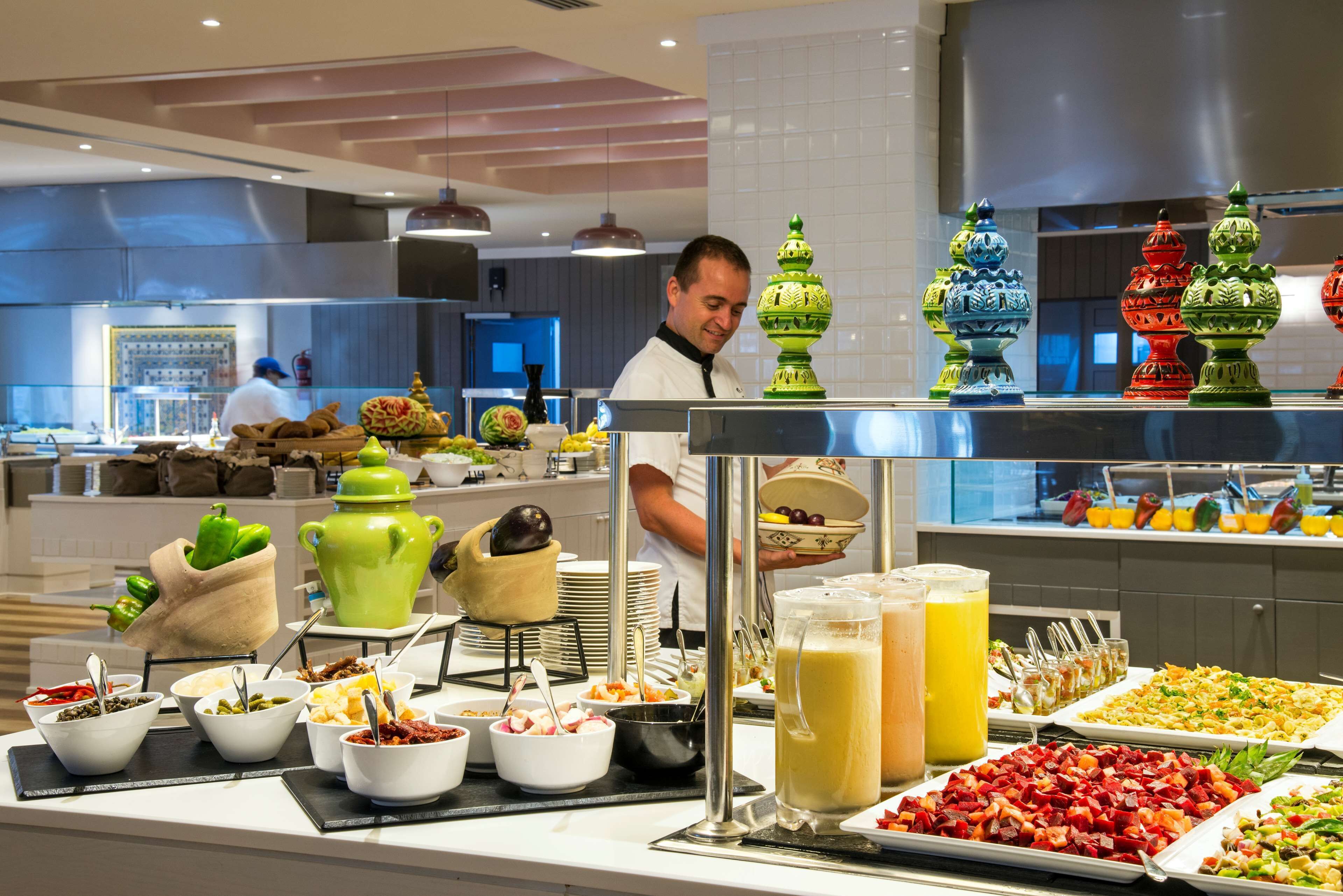 A buffet area with various food items and a chef preparing food.