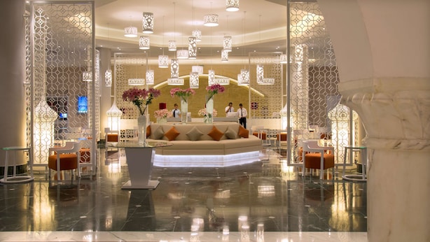 Un moderno vestíbulo de hotel con mostrador de recepción, zona de estar e iluminación decorativa.