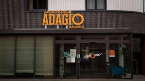Un hotel-apartamento de diseño moderno llamado Adagio Access, con ventanas amplias y un cartel de 'Welcome'.