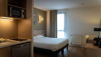 A hotel room with a bed, a microwave, a sink, and a coffee machine.