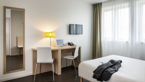 A hotel room with a bed, a desk with a laptop, a chair, a lamp, a telephone, a TV, and a mirror. - Aparthotel Adagio Access Paris Reuilly (Paris)