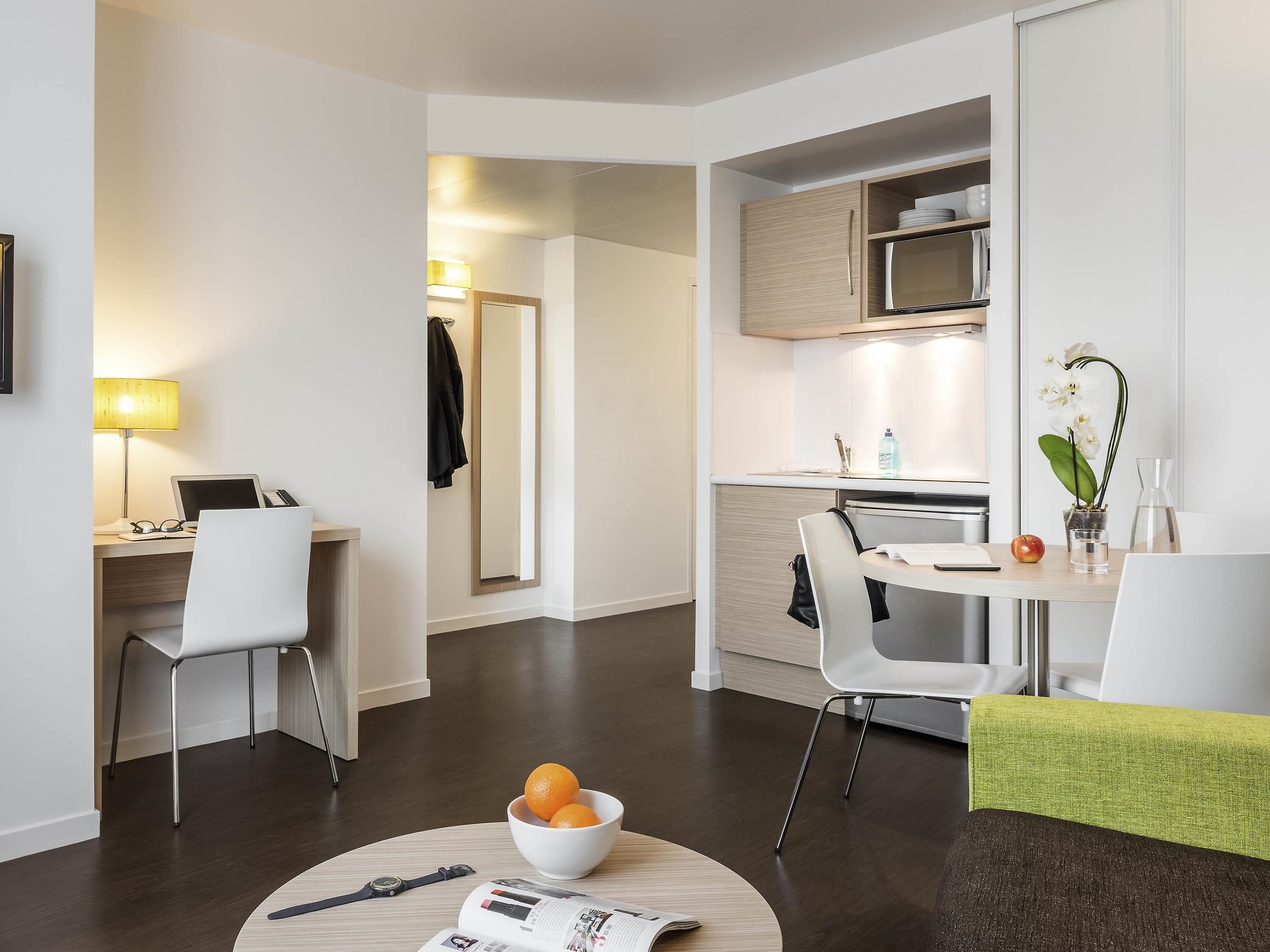 Una habitación de hotel moderna con comedor, cocina y zona de trabajo.