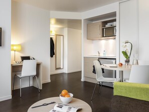 A modern hotel room with a dining area, a kitchen, and a workspace. - Aparthotel Adagio Access Paris Reuilly (Paris)