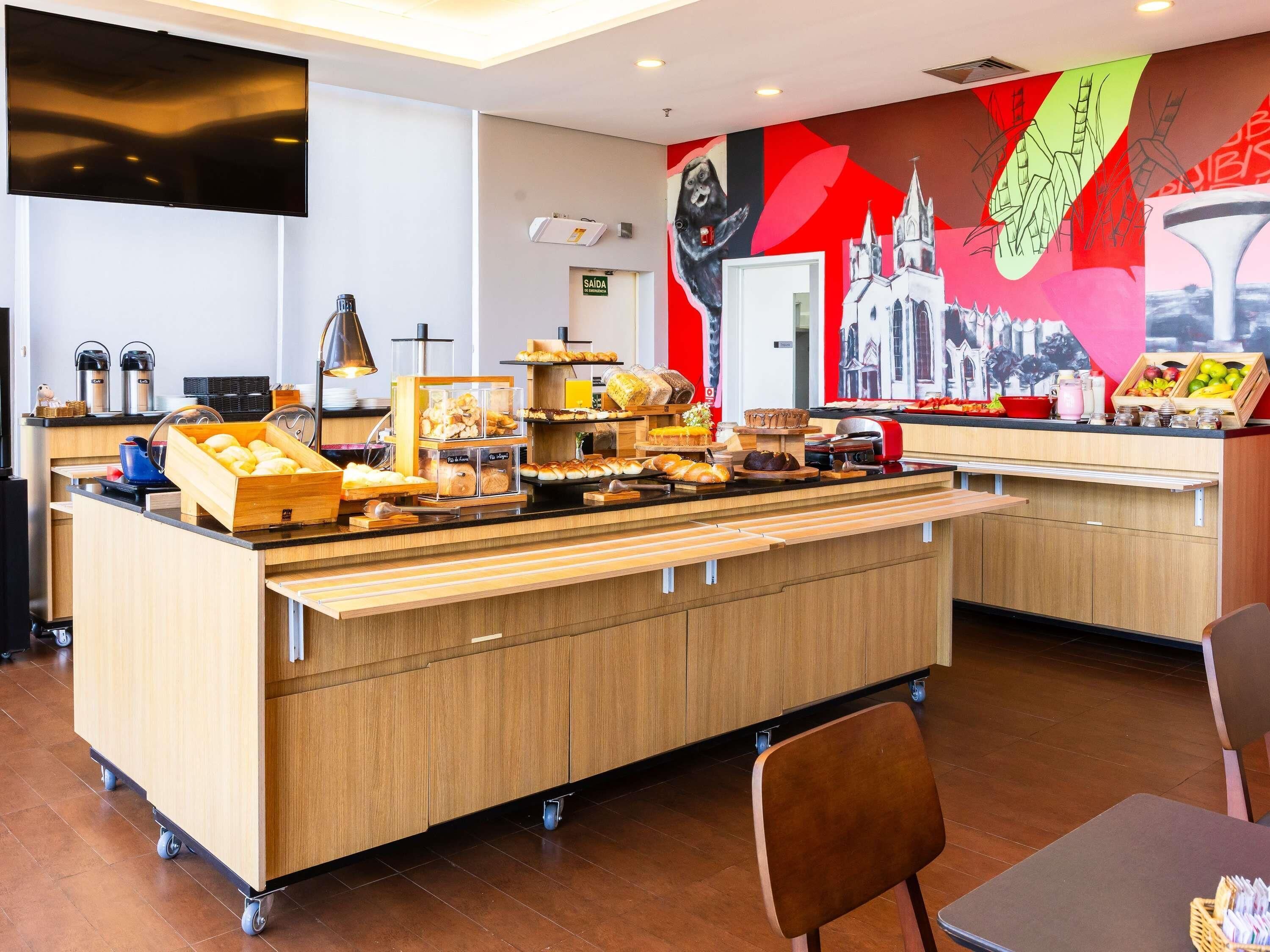 A buffet area with a variety of food items, a coffee station, and a wall mural.