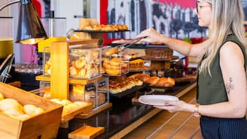 Un mostrador de panadería con diferentes productos horneados expuestos en recipientes de vidrio y cajas de madera.