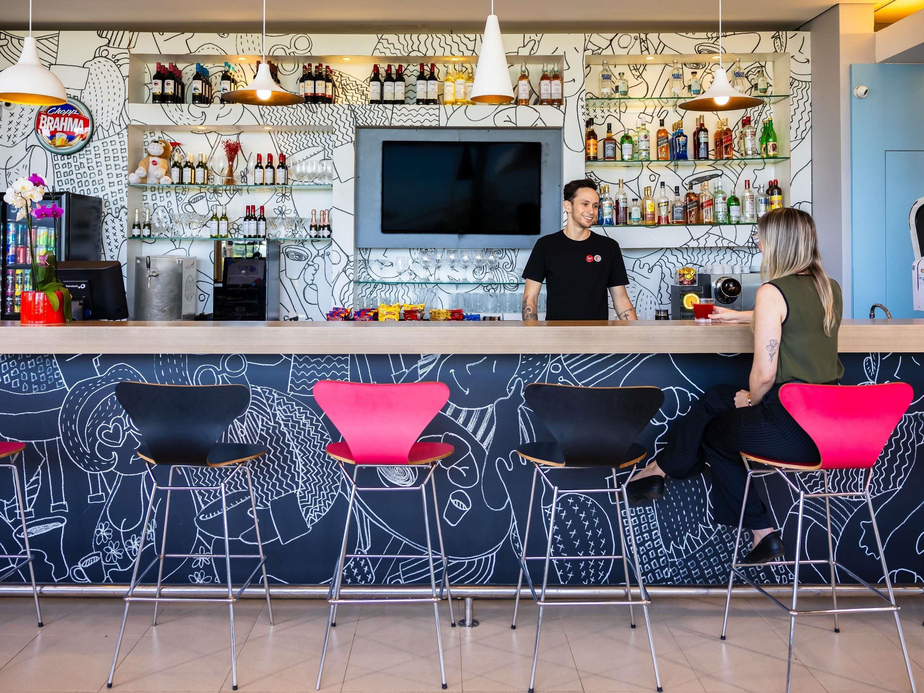 En bar med en bardisk, barstolar och en bartender.