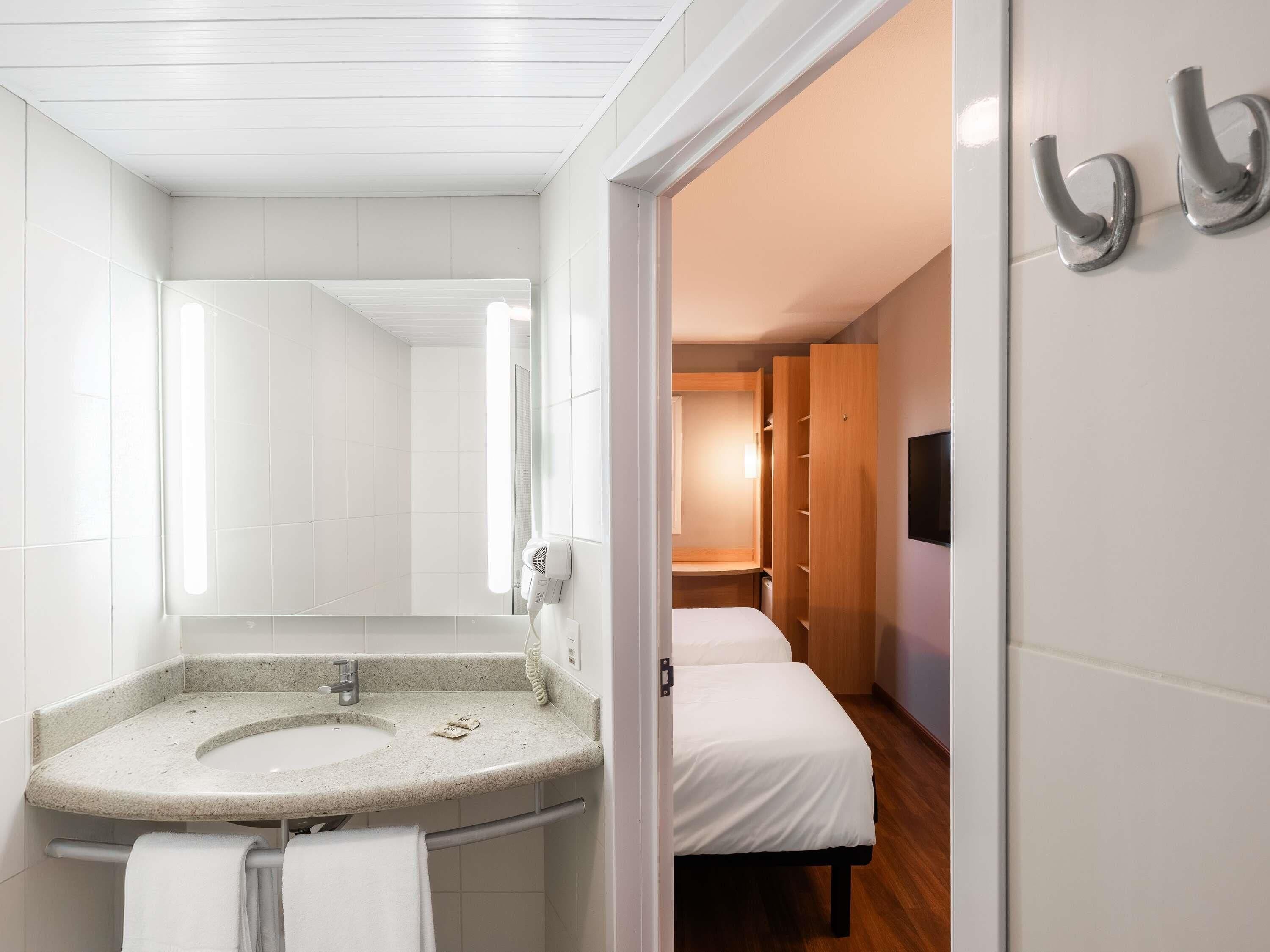 A modern bathroom with a freestanding sink, a mirror, and a towel rack.