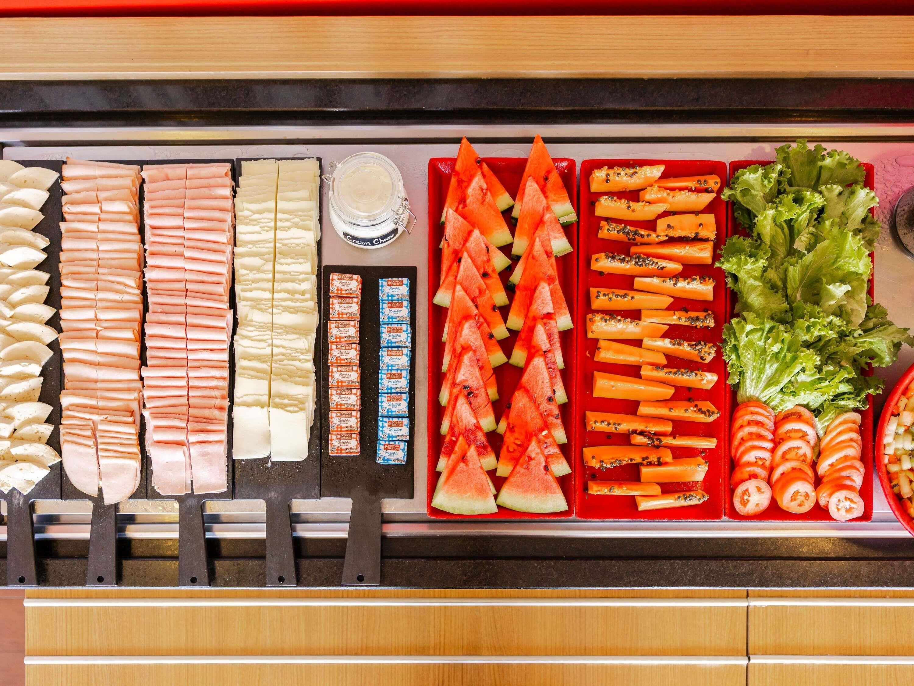 A buffet with various food items including meats, cheeses, fruits, and vegetables.