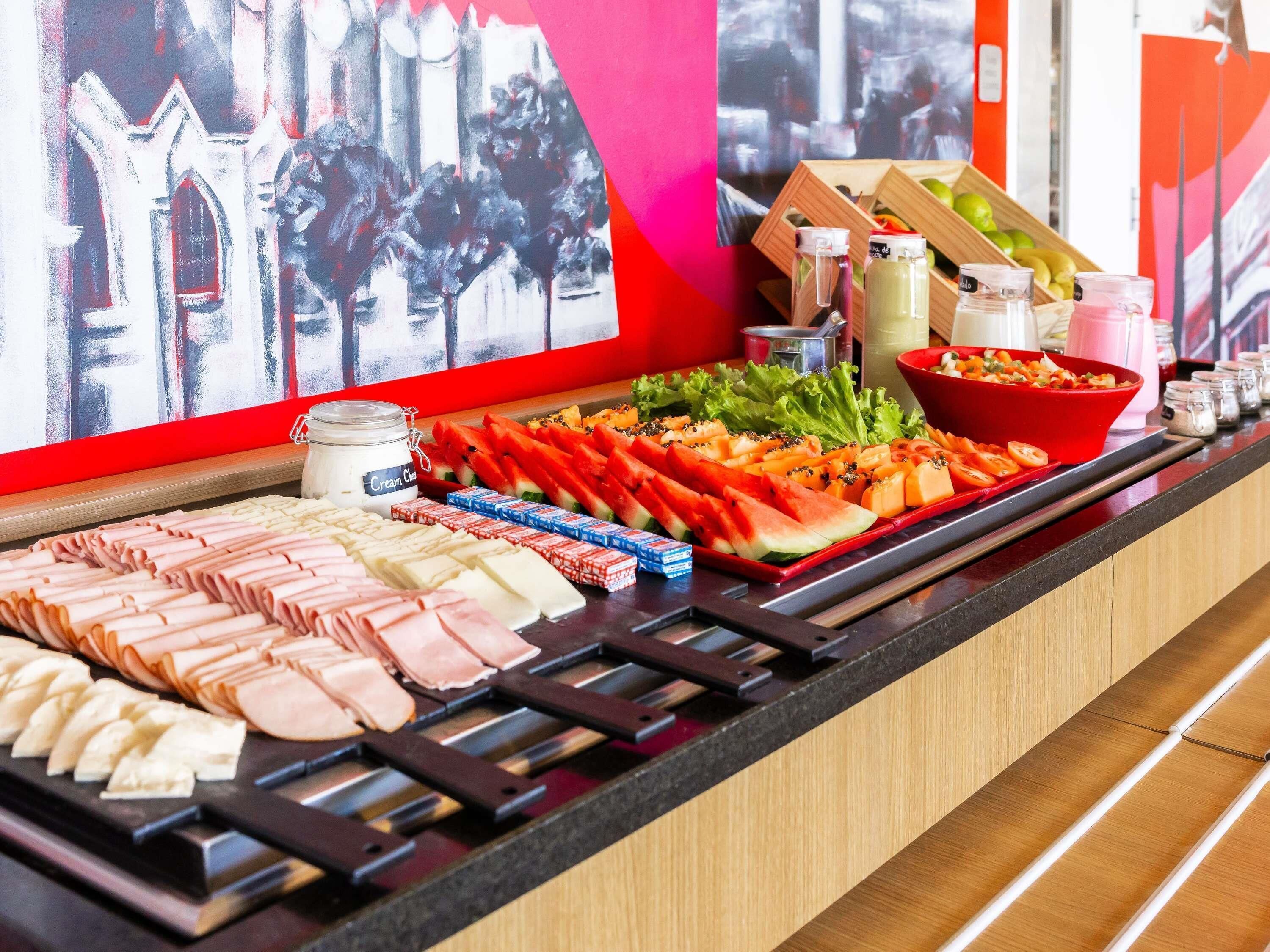 A buffet with various food items, including meats, cheeses, and fresh fruits.