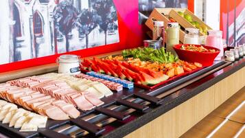 Un buffet proposant une variété de plats, notamment des viandes, des fromages et des fruits frais.