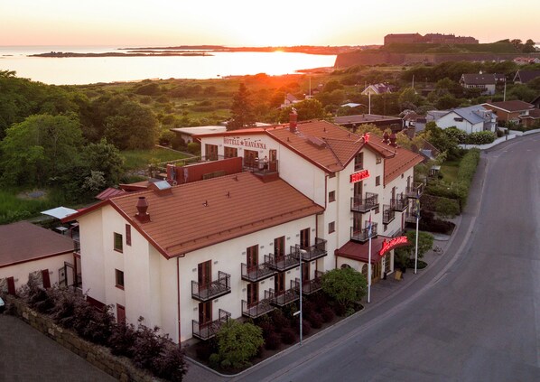 A hotel with a red roof, balconies, and a sign that reads "HOTEL HAVANNA".