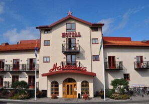 Un hotel con fachada roja y blanca, balcones y una estrella en el techo.