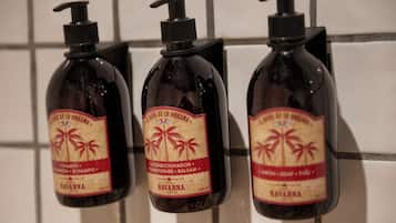 Three bottles of Havana hotel brand toiletries mounted on a tiled wall.