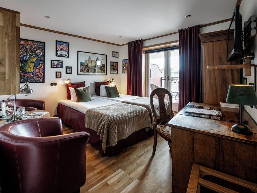 Een hotelkamer met twee bedden, een bureau, een stoel, een houten vloer en kunst aan de muren.
