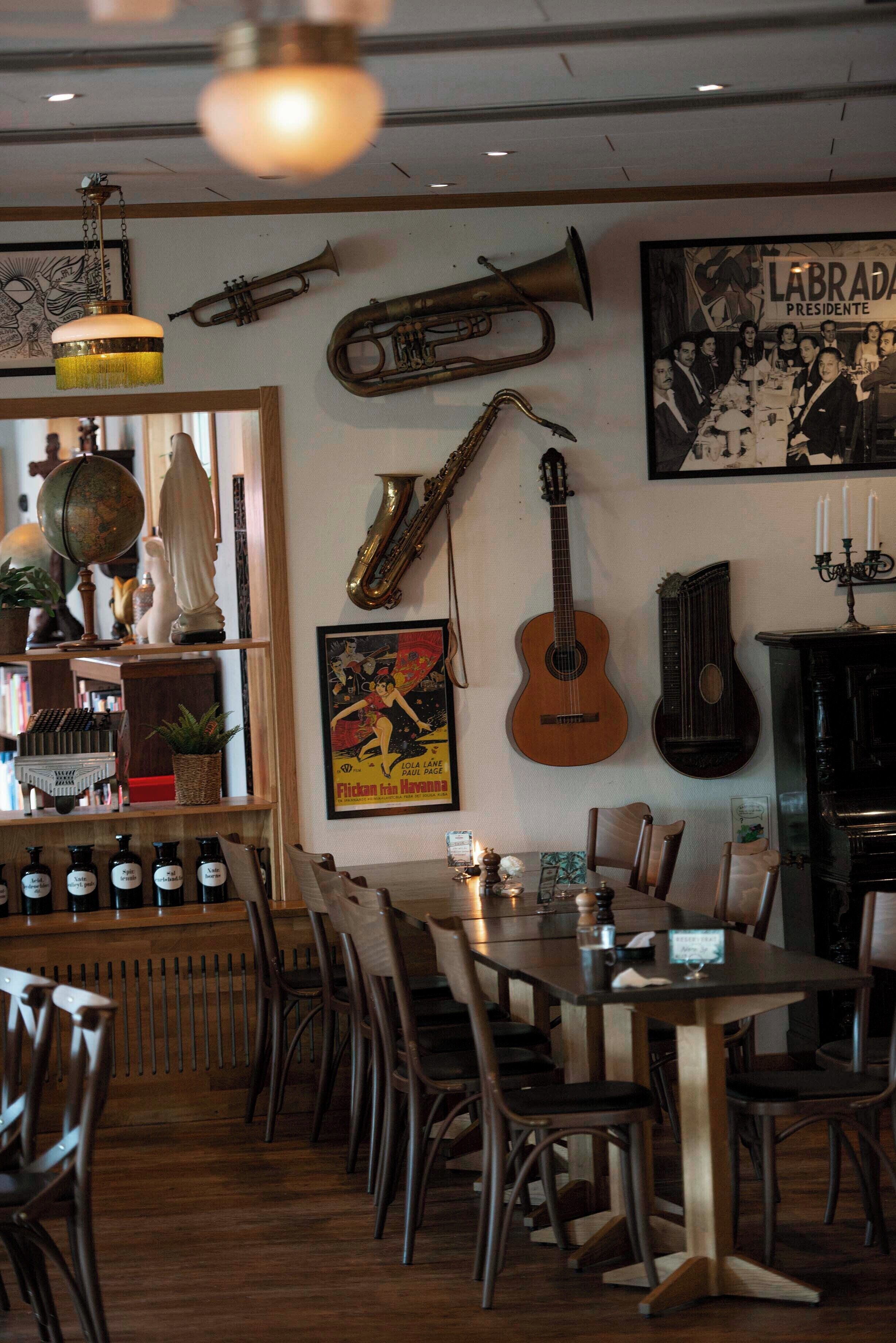A restaurant interior with a wooden dining table, chairs, and a variety of musical instruments on the wall.