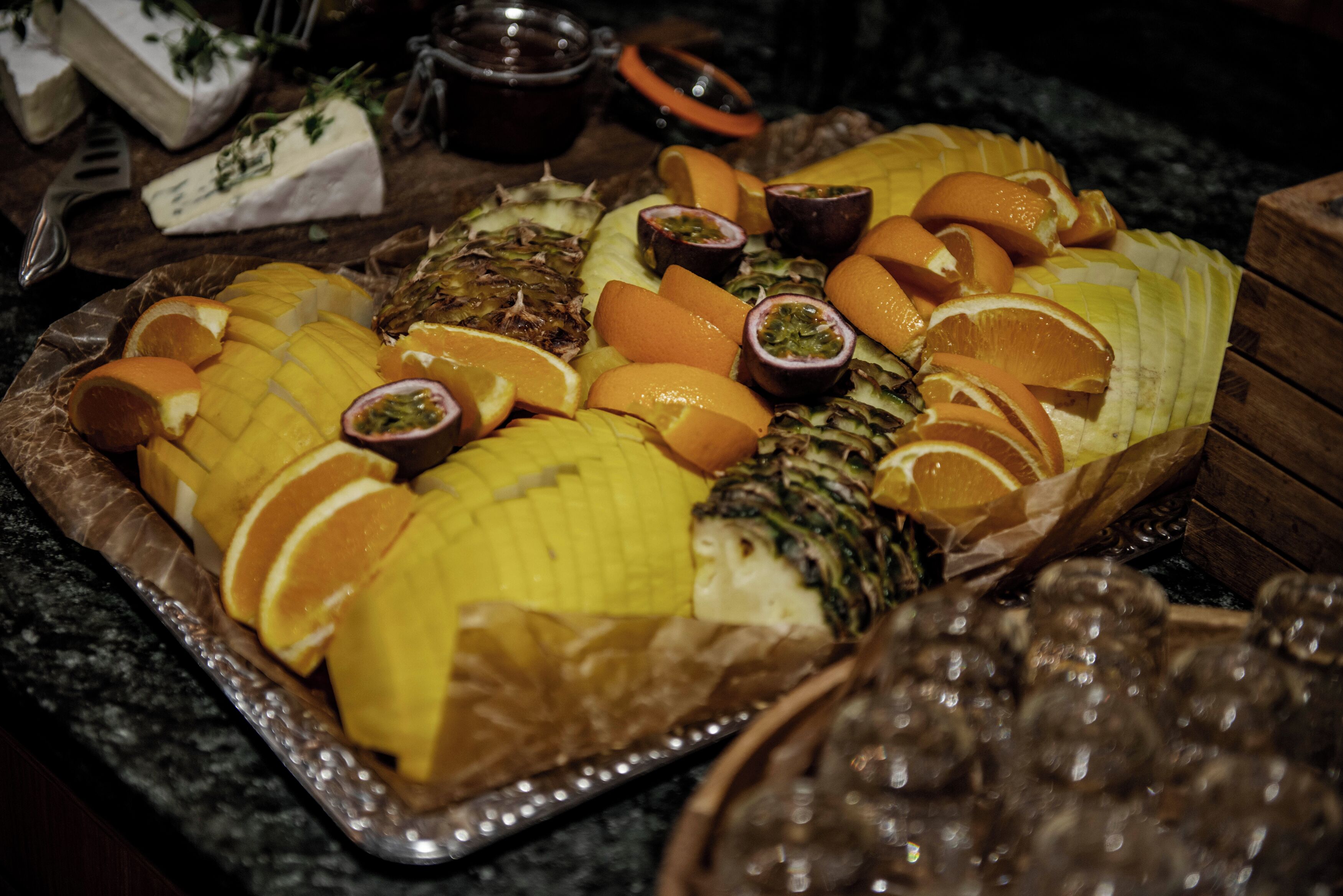 Una bandeja de frutas con diversas frutas y un plato de queso sobre una mesa.